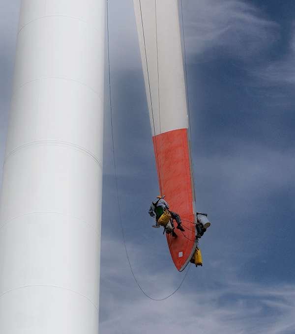 Técnicos suspendidos trabajando en el aspa de un aerogenerador