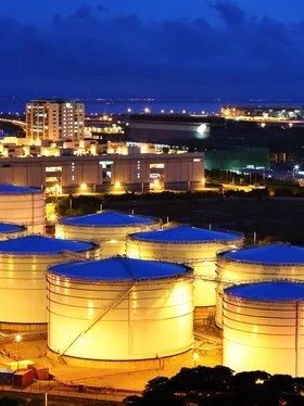 Refinería con tanques de almacenamiento iluminados al anochecer