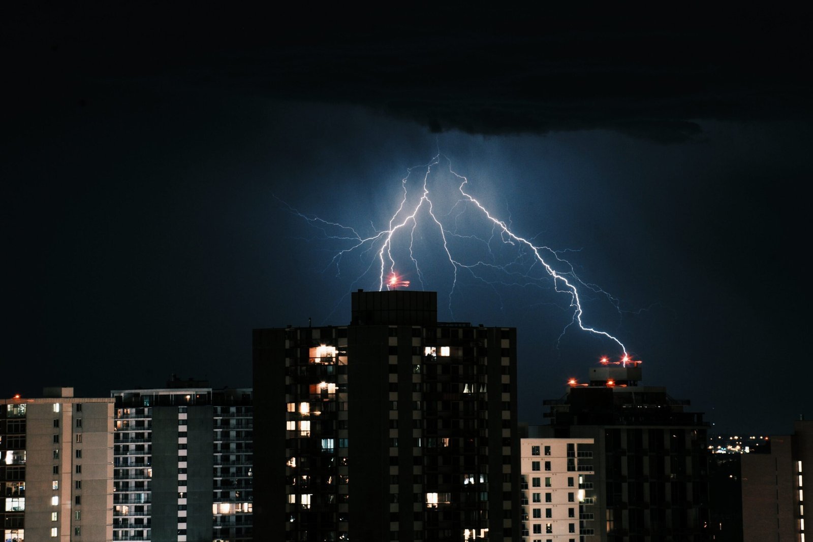 Rayo impactando edificios de una ciudad durante una tormenta nocturna